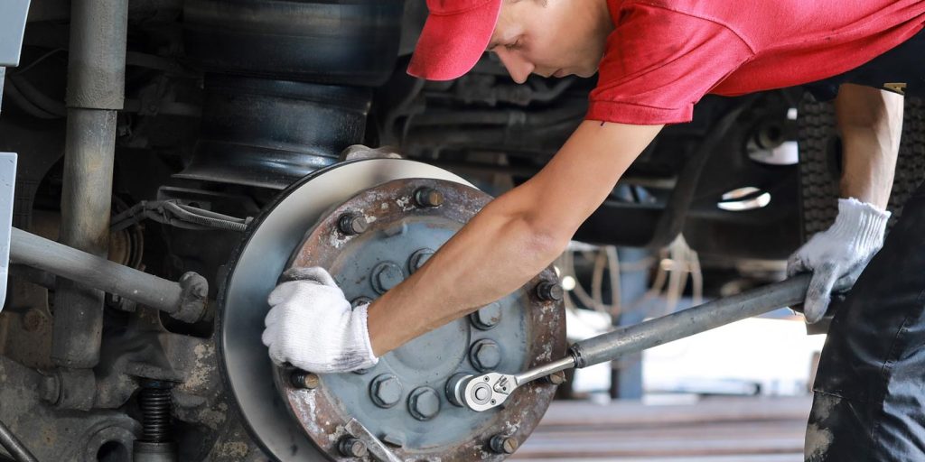 Technician inspecting a semi truck's brake components for wear